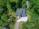 An aerial photograph showing a modern two-story home surrounded by lush forest, driveway, and manicured lawn at 5406 Garrett Rd, Durham, NC 27707