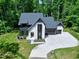Aerial view of a modern two-story home with manicured lawn, concrete driveway, and surrounded by lush trees at 5406 Garrett Rd, Durham, NC 27707