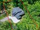 Aerial view of roof of a two-story home surrounded by lush trees with a concrete driveway in a wooded area at 5406 Garrett Rd, Durham, NC 27707