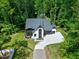 Aerial view of the modern two-story home nestled in a lush, green forest, with a long driveway at 5406 Garrett Rd, Durham, NC 27707