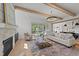 Open living room with wood beam ceiling, stone fireplace, and view of modern kitchen at 30 Spanish Oak Dr, Youngsville, NC 27596