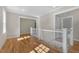Upstairs hallway with hardwood floors, white railing, and neutral paint at 1029 Whitehall Cir, Durham, NC 27713