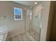 Modern bathroom featuring a glass-enclosed shower with tiled walls and flooring and a window view at 199 Grand Griffon Way, Lillington, NC 27546