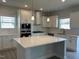 Open kitchen with white cabinetry, stainless steel appliances, and a large central island at 499 Glenkirk Pl # 101, Garner, NC 27529