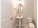 Clean powder room with pedestal sink, toilet, and oval mirror at 499 Glenkirk Pl # 101, Garner, NC 27529