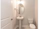Powder room featuring a pedestal sink, oval mirror, and toilet at 499 Glenkirk Pl # 101, Garner, NC 27529