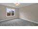 A carpeted bedroom features a large window with neighborhood views and a stylish light fixture at 1125 Brookfield Dr, Gibsonville, NC 27249