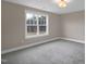 A bright bedroom offers soft gray carpet and a window with a view of the trees at 1125 Brookfield Dr, Gibsonville, NC 27249