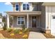 Inviting front entrance featuring a covered porch, verdant landscaping, and a charming wood door at 1125 Brookfield Dr, Gibsonville, NC 27249