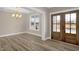 Open concept dining room featuring hardwood floors, modern lighting, and a wooden double door at 1129 Brookfield Dr, Gibsonville, NC 27249