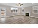 Living room features wood-look flooring, fireplace, three large windows, and white trim at 1129 Brookfield Dr, Gibsonville, NC 27249