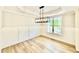 Bright dining room with wainscoting, modern chandelier, tray ceiling, and wood-look floors at 2613 Silver Gate Ct, Wake Forest, NC 27587