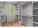 Spacious walk-in closet with built-in shelving, drawers, hardwood floor, and window at 330 Hidden Lake Dr, Youngsville, NC 27596