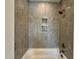 Bathroom with a tub and shower featuring neutral tile and built-in niche at 627 Georgetown Rd, Raleigh, NC 27608