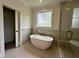 Luxurious bathroom with stand alone tub, glass shower, and neutral tile at 627 Georgetown Rd, Raleigh, NC 27608