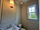 Elegant powder room featuring marble countertop and paneled walls and a pendant light at 627 Georgetown Rd, Raleigh, NC 27608