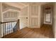 Hallway with hardwood floors and a view of the stairway featuring wood and iron railings at 627 Georgetown Rd, Raleigh, NC 27608