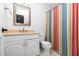 Bright bathroom with a colorful striped shower curtain, white vanity, and a framed mirror at 6413 English Oaks Dr, Raleigh, NC 27615