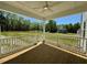 Inviting covered back porch with ceiling fan and white railings overlooks a beautiful lawn and wooded area at 235 Grand Griffon Way, Lillington, NC 27546