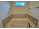 This bathroom features a soaking tub with tile surround, brushed nickel hardware, and an exterior window at 235 Grand Griffon Way, Lillington, NC 27546