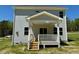 Rear exterior showcasing a cozy covered porch with steps leading down to the yard, complemented by light siding at 235 Grand Griffon Way, Lillington, NC 27546