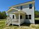 Rear exterior of a home featuring light siding, a covered porch, and steps to the backyard at 235 Grand Griffon Way, Lillington, NC 27546
