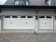 White garage doors with black hardware, complemented by a brick facade, enhancing the home's curb appeal at 65 Firefly Overlook, Pittsboro, NC 27312