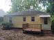 The exterior back view of the home features a small deck and a yellow siding at 1202 N Duke St, Durham, NC 27701