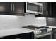 Kitchen with stainless steel appliances, white backsplash and dark modern cabinets at 2337 E Main St, Durham, NC 27703