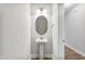 Stylish powder room featuring a pedestal sink, oval mirror, modern lighting, and hardwood flooring at 553 Eversden Dr, Zebulon, NC 27597