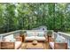 Spacious deck features comfy seating and a wooden coffee table, surrounded by lush trees at 116 Oak Ridge Dr, Willow Springs, NC 27592