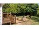 Landscaped backyard patio area with deck access, stone base, seating, grill, and wooded backdrop at 605 Quarry St, Raleigh, NC 27601
