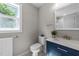 Bathroom featuring a blue vanity, a white countertop sink, and a bright window above the toilet at 605 Quarry St, Raleigh, NC 27601