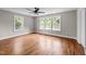 Spacious bedroom featuring hardwood floors, a ceiling fan, and bright natural light from the multiple windows at 605 Quarry St, Raleigh, NC 27601