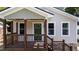 Close up of covered front porch with a wood railing and a striking green front door at 605 Quarry St, Raleigh, NC 27601