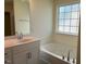 Bathroom featuring white cabinets, bathtub and shower combo, large mirror, and natural light at 253 Plains Dr # 264, Burlington, NC 27217