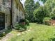 Beautiful backyard with a stone home, lush lawn, manicured landscaping, and mature trees at 2501 Kenmore Dr, Raleigh, NC 27608