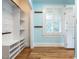 Walk-in closet with open shelving, white storage cabinet, and warm wood floors at 2501 Kenmore Dr, Raleigh, NC 27608