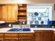 Bright kitchen showing wood cabinets, a dual basin blue sink, and a window shelf with decorative plates at 2501 Kenmore Dr, Raleigh, NC 27608