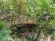Rustic stone bridge over a creek, surrounded by lush greenery, offers a tranquil garden setting at 2501 Kenmore Dr, Raleigh, NC 27608