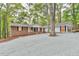 Stunning home with brick and white siding, featuring a large gravel driveway and lush, mature trees at 128 Dixie Dr, Chapel Hill, NC 27514