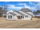 Back exterior view of a beige home with a covered porch and a lawn waiting for new grass at 3109 Petrea Ct # 39, Angier, NC 27501