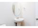 Bathroom with a stylish pedestal sink, oval mirror, and modern fixtures at 7417 Prato Ct, Wendell, NC 27591