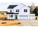New construction home with a three-car garage, white siding, dark roof, and covered porch with blue door at 7417 Prato Ct, Wendell, NC 27591
