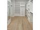 Large walk-in closet boasts wood floors, built-in shelving, cabinets and a dressing mirror at 2525 Silas Peak Ln, Apex, NC 27523