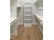 Spacious walk-in closet features built-in shelving, wood floors and bright, neutral paint at 2525 Silas Peak Ln, Apex, NC 27523
