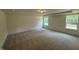 Large bedroom featuring neutral carpet, tray ceiling, and two windows providing ample light at 135 Green Haven Blvd # 1, Youngsville, NC 27596