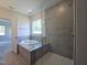 Modern bathroom featuring a large tub, separate shower, tile surround, and natural light from a window at 145 Green Haven Blvd # 83, Youngsville, NC 27596