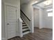 Hallway with hardwood floors, stairs with dark wood steps, and white paneled doors at 145 Green Haven Blvd # 83, Youngsville, NC 27596