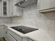 Close-up of the kitchen with a modern cooktop and elegant marble tile backsplash at 145 Green Haven Blvd # 83, Youngsville, NC 27596